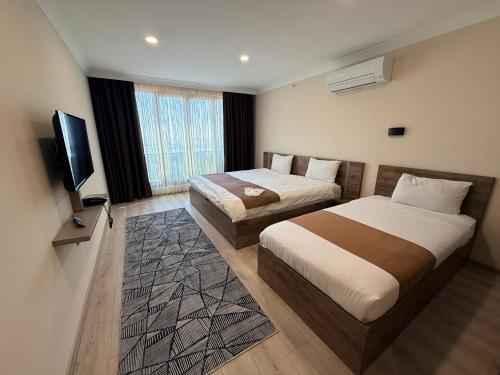 a hotel room with two beds and a flat screen tv at Rena Grand Residence & Suit in Trabzon
