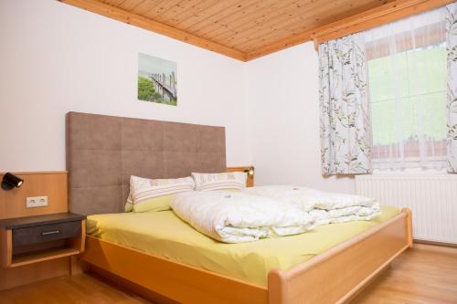 a bedroom with a bed with yellow sheets and a window at Lochgrubgut in Altenmarkt im Pongau