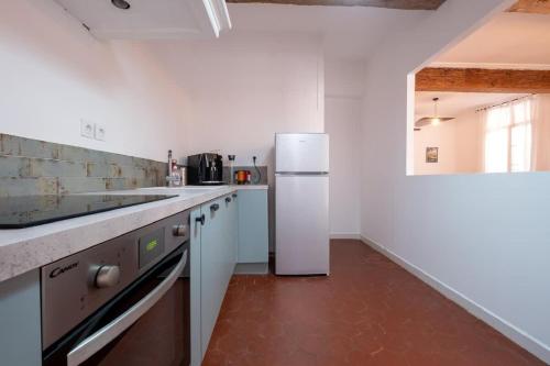 a kitchen with a white refrigerator in a room at Le Cocon d'Or Perpignan Centre in Perpignan
