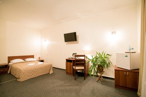 a bedroom with a bed and a desk and a tv at Dinaburg SPA Hotel in Daugavpils