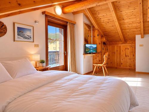 a bedroom with a large white bed and a television at Hotel Aquila in Livigno