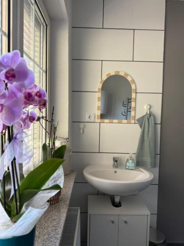 a bathroom with a sink and a vase of purple flowers at Caroline in Leoben
