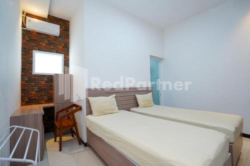 a bedroom with two beds and a chair in it at Griya Borobudur Malang Syariah RedPartner in Blimbing