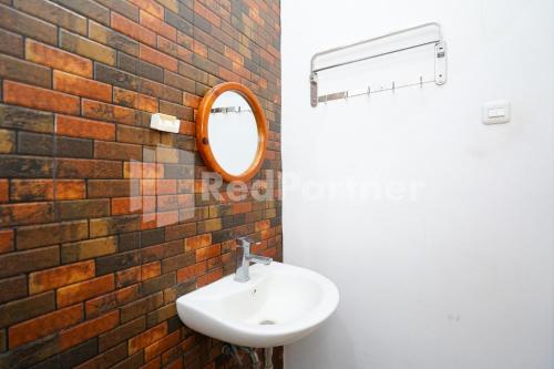 a bathroom with a sink and a mirror on a brick wall at Griya Borobudur Malang Syariah RedPartner in Blimbing