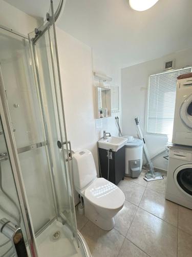 a bathroom with a shower and a toilet and a sink at Cozy 2-Bedroom Apartment in Kristiansand