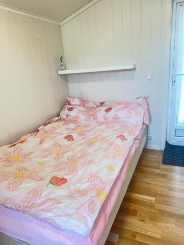 a bed with a pink and yellow blanket on it at Cozy 2-Bedroom Apartment in Kristiansand