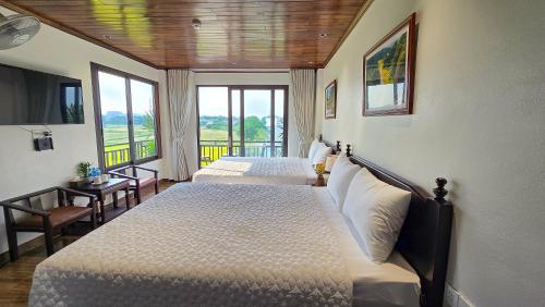 two beds in a hotel room with a balcony at Tam Cốc Hà Anh Hotel in Văn Lâm