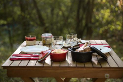 una mesa de picnic con comida y copas de vino. en Chrysalide Saint Martin en Nérac