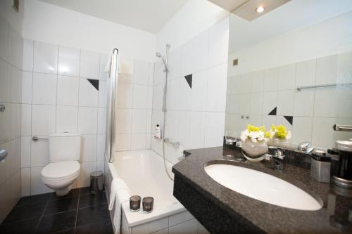 een badkamer met een wastafel, een toilet en een bad bij Hotel Alt Riemsloh in Melle