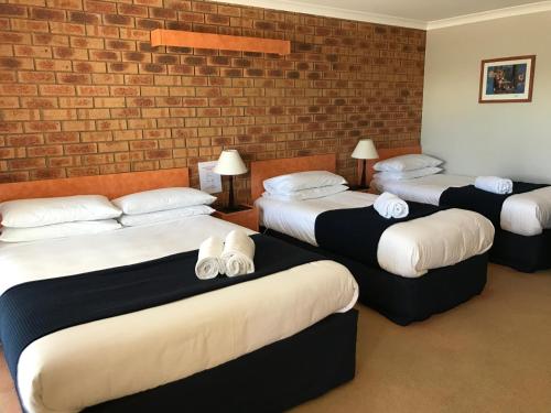 four beds in a room with a brick wall at Avoca Motel in Avoca