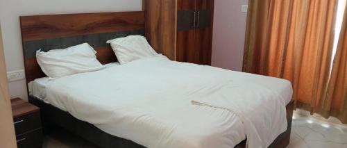 a bed with white sheets and pillows in a bedroom at Elixir Boarding & Lodging in Bangalore