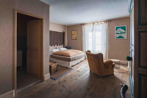a bedroom with a bed and a chair in it at Les Greniers in Myon