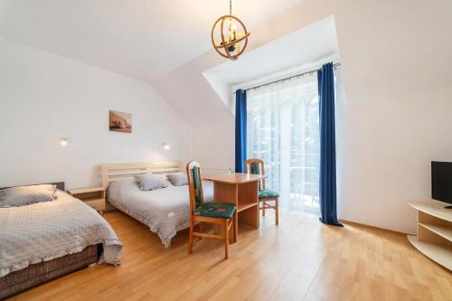 a bedroom with a bed and a desk and a table at Willa Promyk in Jastarnia
