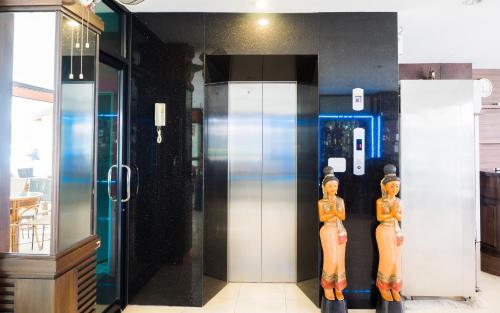 two wooden mannequins standing in front of a glass elevator at Patong Moon Inn Residence in Patong Beach