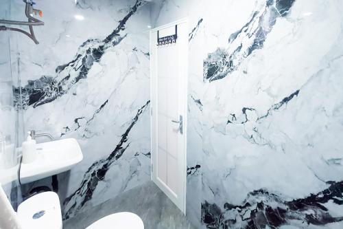 a bathroom with a white marble wall at Graha Martadinata Syariah Mitra RedDoorz in Tasikmalaya