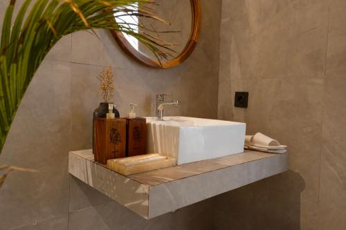 a bathroom with a white sink and a mirror at Penida Green Palm Cottage in Nusa Penida