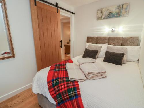 a bedroom with a bed with a plaid blanket on it at Rosalin Cottage in Irvine