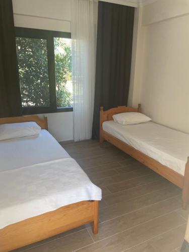 two beds in a room with a window at Muğladaki Eviniz in Muğla