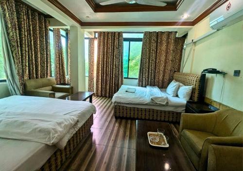 ein Hotelzimmer mit zwei Betten und einer Couch in der Unterkunft New Islamabad Hotel in Islamabad