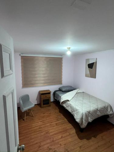 a bedroom with a bed and a window with a chair at Hostel Campus Lircay in Talca