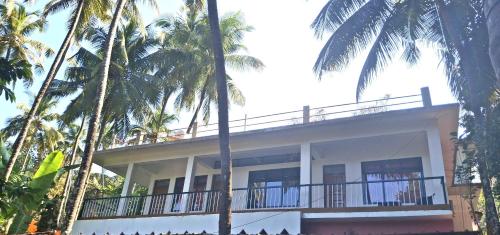 a building with palm trees in front of it at Rooms In Canacona in Canacona