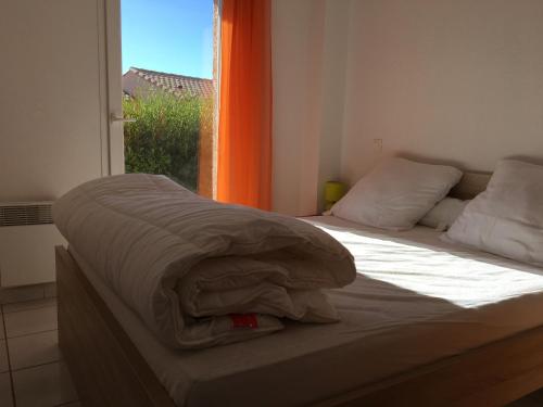 a bed with a blanket on it in a room with a window at T3 vue mer et plage, avec wifi et parking in Saint Pierre La Mer