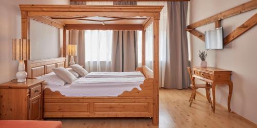 a bedroom with a wooden canopy bed and a desk at I AM HOTELS Graz-Seiersberg in Graz