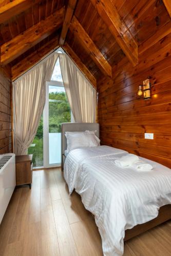 a bedroom with a large white bed in a room with wooden walls at KayakHotel in Ndërlisaj