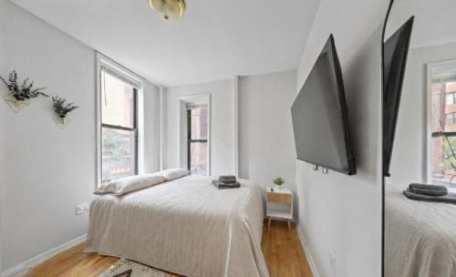 a white room with two beds and a flat screen tv at The NYC Value Room near Times Square & Broadway - Private Room with shared bathroom in New York