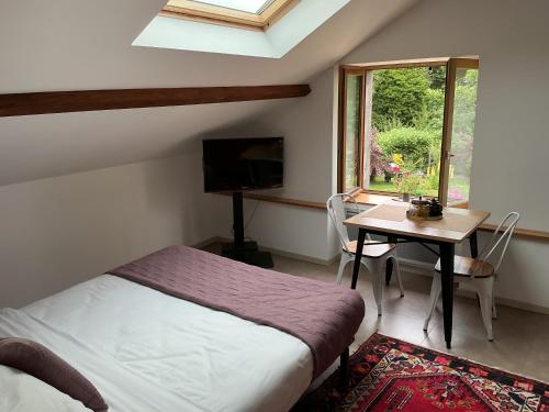 a bedroom with a bed and a table and a window at Chez Rose-Laure in Grandviala