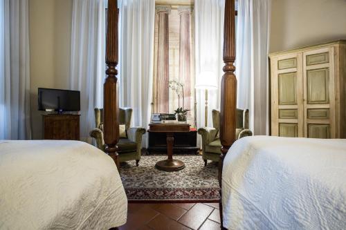 a bedroom with two beds and a desk and a television at Hotel Burchianti in Florence