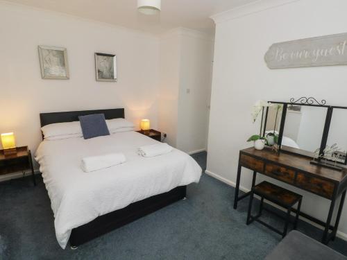 a bedroom with a bed and a desk and a mirror at Cwtch Ar Y Mor in Burry Port