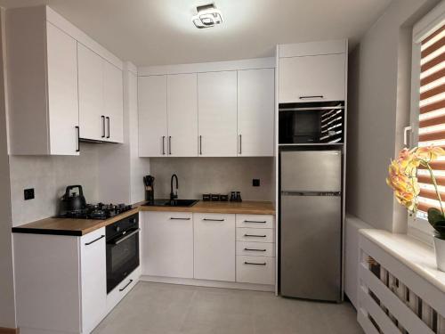 a kitchen with white cabinets and a stainless steel refrigerator at Apartament Ryki in Ryki