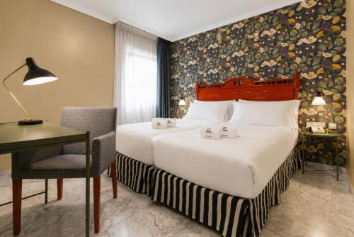 a hotel room with a bed and a desk and a chair at Petit Palace Puerta de Triana in Seville