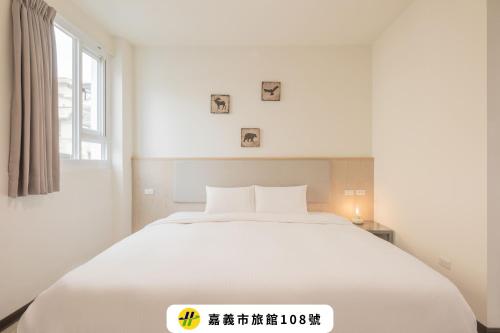 a white bed in a white room with a window at Meant To Be in Chiayi City