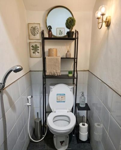 a bathroom with a toilet with a shelf above it at RR Travertine House Cikarang in Jatirarangan