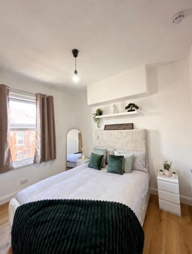 ein Schlafzimmer mit einem großen weißen Bett und grünen Kissen in der Unterkunft Cloud Quarters 3 in Amley