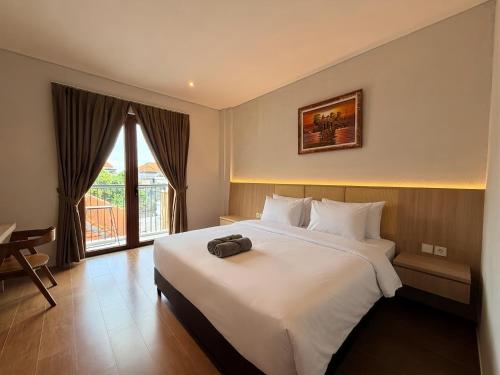 a bedroom with a large white bed and a window at Kalpa Tree Co-living in Canggu