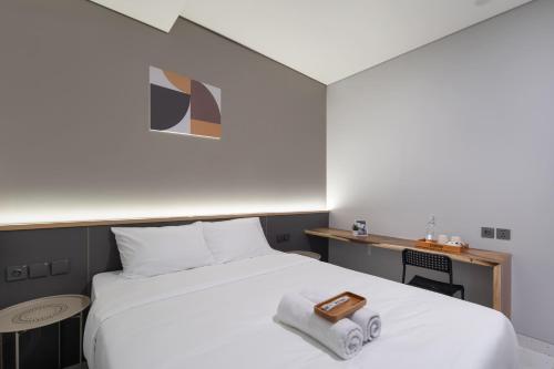 a bedroom with a white bed with a towel on it at Cove Vaia in Bandung
