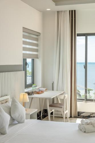 a bedroom with a bed and a table with a view of the ocean at Casa De Sol Resort - Wuwei Retreat in Phú Quốc