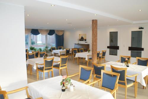 a restaurant with white tables and blue chairs at Haus Sonnenwinkel in Bad Laer
