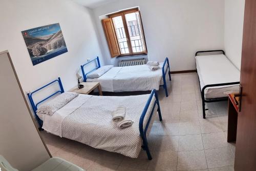 a room with three beds and a window at Ostello del Parco di Monte Cucco in Costacciaro