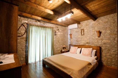 a bedroom with a bed and a stone wall at Villa Shuaipaj in Gjirokastër