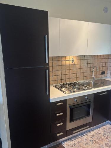 a kitchen with a black refrigerator and a stove at Nice Gecko in Baveno