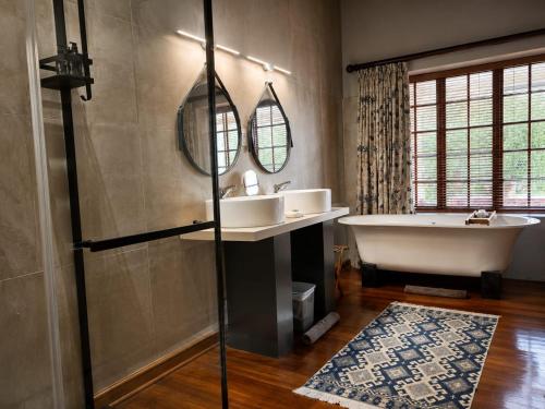 a bathroom with a tub and a sink and mirror at De Zeekoe Guest Farm in Oudtshoorn