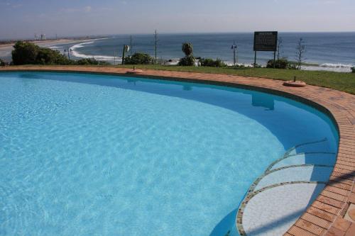 a large blue swimming pool next to a beach at First Group Brookes Hill Suites in Summerstrand