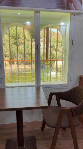a table and a chair in a room with windows at منتجع خيال رفيف in Ḩarshaf