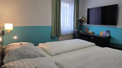 a bedroom with two beds and a desk and a television at Hotel König in Vienna