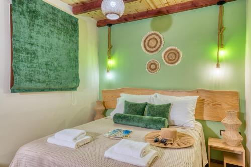a green bedroom with a bed with towels on it at Olive & Wave Cottage in Karousádes