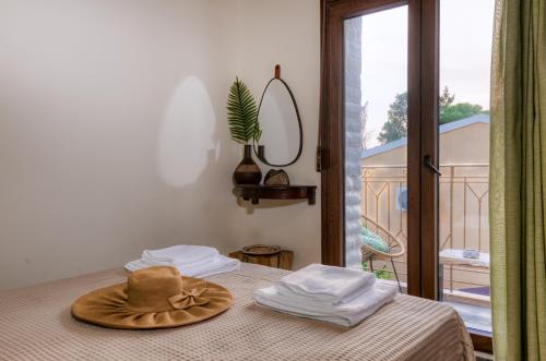 a hat on a bed in a room with a window at Olive & Wave Cottage in Karousádes